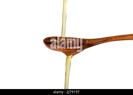 Sonnenblumenöl gießt von oben auf einen Holzlöffel und fließt auf weißem Grund hinunter. Speicherplatz kopieren. Stockfoto