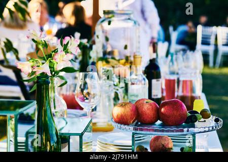 Serviert Banketttisch mit Äpfeln, Alkohol und verschiedenen Utensilien Stockfoto