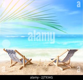 Ferienurlaub Hintergrundkonzept - zwei Strandliegen unter Palmen am Sommerstrand Stockfoto