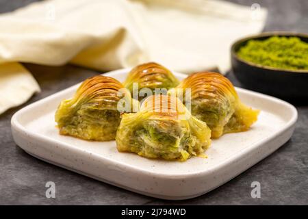 Muschel Baklava. Pistazien-Baklava auf dunklem Hintergrund. Köstlichkeiten der mediterranen Küche. Nahaufnahme. Lokaler Name midye baklava Stockfoto