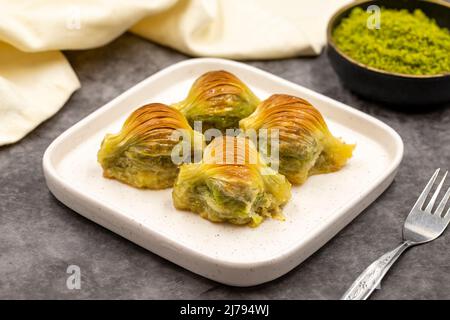 Muschel Baklava. Pistazien-Baklava auf dunklem Hintergrund. Köstlichkeiten der mediterranen Küche. Nahaufnahme. Lokaler Name midye baklava Stockfoto