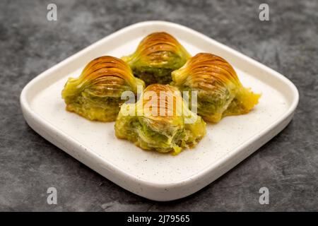 Muschel Baklava. Pistazien-Baklava auf dunklem Hintergrund. Köstlichkeiten der mediterranen Küche. Nahaufnahme. Lokaler Name midye baklava Stockfoto