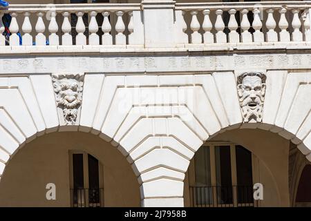 Brescia. Mittelalterlicher Broletto Palast, XII-XXI Jahrhundert. Weiße Steinbögen mit Keystones und grotesken menschlichen Masken von Wasserspeiern. Lombardei, Italien, Europa Stockfoto