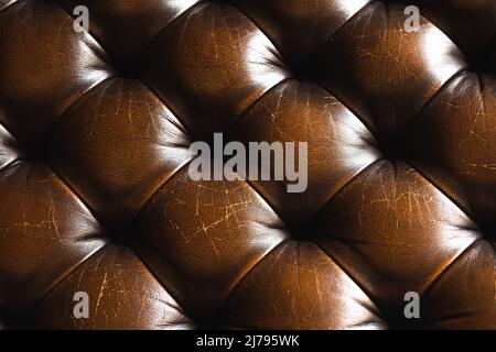 Tiefe, reiche Echtlederstruktur. Vintage dunkelbraunes Sofa mit Knöpfen für Hintergrund. Dekorationsdesign. Luxus-Mode und Lifestyle-Konzept Stockfoto