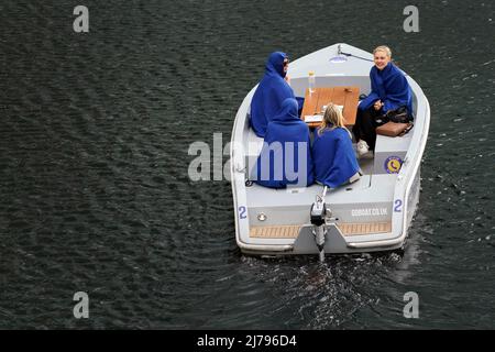 Vier Frauen schützen sich auf einem Boot in den Londoner Docklands im Osten Londons vor dem Regen. Bilddatum: Samstag, 7. Mai 2022. Stockfoto