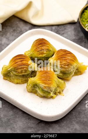 Muschel Baklava. Pistazien-Baklava auf dunklem Hintergrund. Köstlichkeiten der mediterranen Küche. Nahaufnahme. Lokaler Name midye baklava Stockfoto