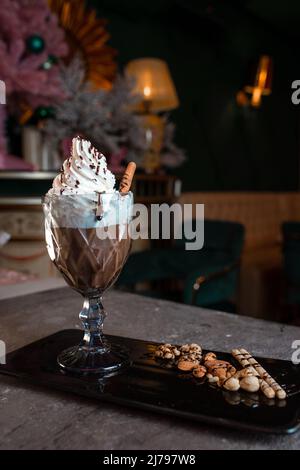 Süßer Milchshake mit Creme und Zimt in einem Glas. Stockfoto