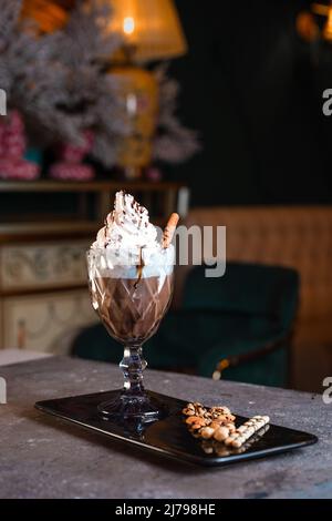 Süßer Milchshake mit Creme und Zimt in einem Glas. Stockfoto