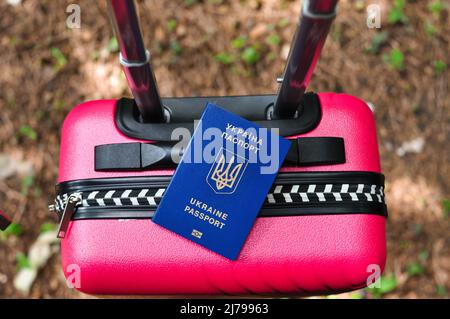 Biometrischer ukrainischer Pass des Flüchtlings auf rosa Reisetasche Stockfoto