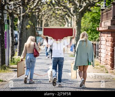 07. Mai 2022, Hessen, Frankfurt/Main: Ein Mann trägt einen Sitz auf dem Kopf und mit den Armen und geht weg vom Flohmarkt, der regelmäßig samstags auf einer dafür gesperrten Straße am Mainufer stattfindet. Foto: Frank Rumpenhorst/dpa Stockfoto