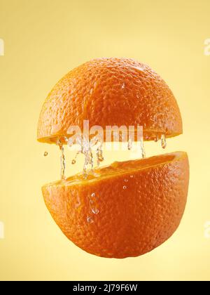 Orangensaft aus Orangenfrüchten in Bewegung. Spritzer Saft Stockfoto