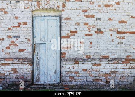 Alte hölzerne Eingangstür auf weißem und rotem Backsteinwand Hintergrund Stockfoto