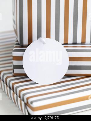 Geschenke mit leerem runden Geschenkanhänger aus nächster Nähe. Geschenkschachteln in Gestreiftem Papier verpackt. Weihnachten, Neujahr, Geburtstag, Anniversary Label Mockup Stockfoto