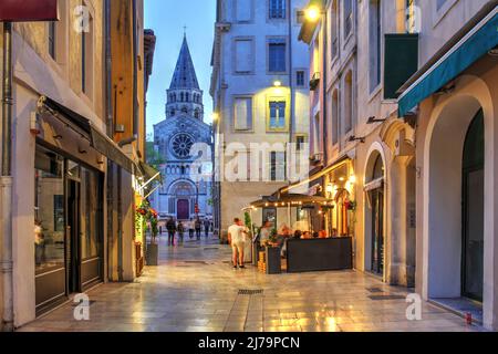 Straßenszene entlang der Rue de la Madelaine in der Altstadt von Nîmes, Frankreich mit der St. Paul Kirche im Hintergrund. Stockfoto