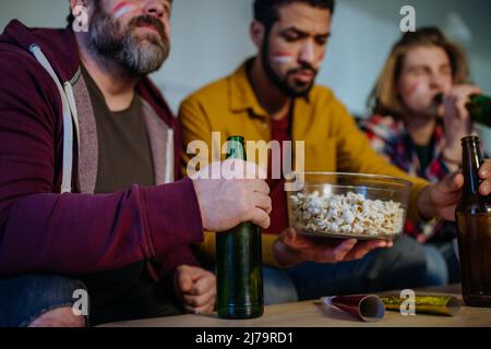 Nahaufnahme der Freunde von Fußballfans, die ein Spiel ansehen und Popcorn essen. Stockfoto
