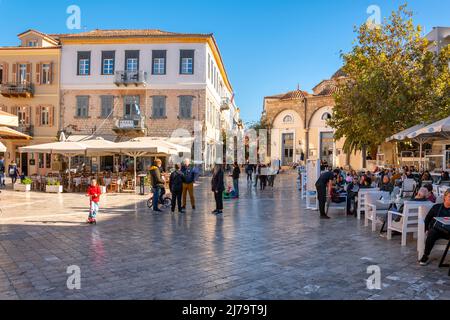 Griechen und Touristen genießen einen sonnigen Herbsttag auf dem Syntagma-Platz in der historischen Altstadt von Nafplion, Griechenland. Stockfoto