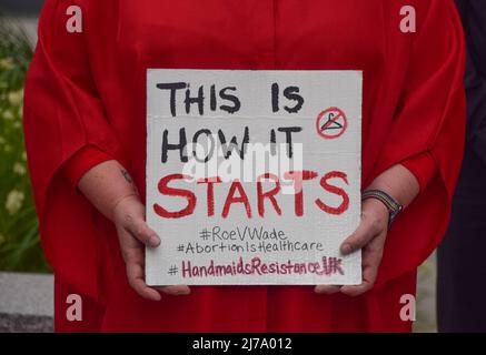 London, Großbritannien. 7. Mai 2022, London, England, Vereinigtes Königreich: Ein Aktivist, der eine Handmaid's Tale Kleidung trägt, hält ein Schild mit der Aufschrift 'This is How IT Starts'. Wahlproter versammelten sich vor der US-Botschaft in London, als Berichte über den Fall von Roe v. Wade auftauchten, was den Weg für ein Verbot von Abtreibungen in einem Großteil der USA ebnete. (Bild: © Vuk Valcic/ZUMA Press Wire) Bild: ZUMA Press, Inc./Alamy Live News Stockfoto