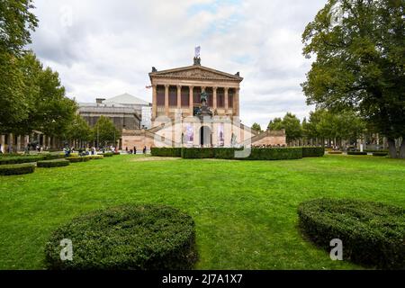 Touristen besuchen die National Gallery oder Alte Nationalgalerie an einem bewölkten Tag auf der Museumsinsel in Berlin, Deutschland. Stockfoto