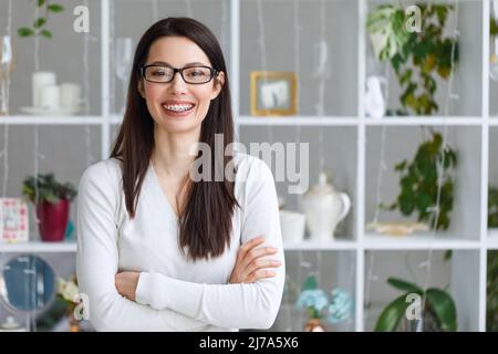 Glückliche junge Frau schaut auf die Kamera und lächelt. Stockfoto