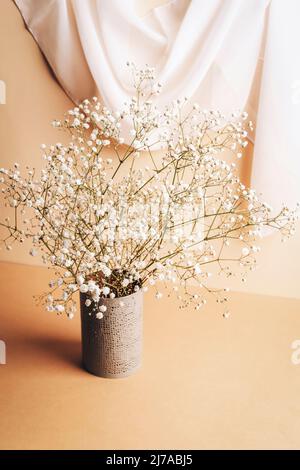 Gypsophila blüht in Vase auf beigem Tisch. Stillleben. Stockfoto