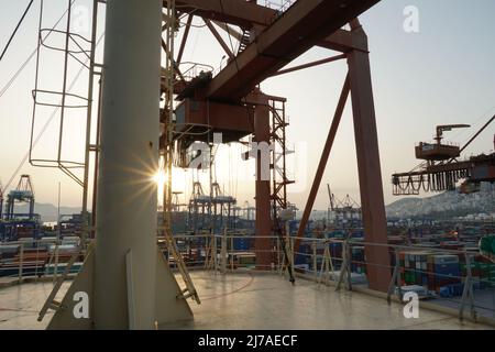 Blick vom Schiff auf den Hochbau großer Portalkrane in horizontaler Position, die auf den Frachtbetrieb der Containerschiffe in Piräus, Griechenland, warten. Stockfoto