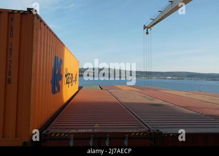 Oranger Container von Hapag Lloyd Reederei wird auf der obersten Ebene im hinteren Teil des Containerschiffes mit Kränen verladen verlassen Hafen von Koper Slowenien. Stockfoto