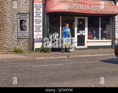 Motorradfahrer in Lederanzug telefonieren vor einem Geschäft in Skegness, Lincolnshire, Großbritannien Stockfoto