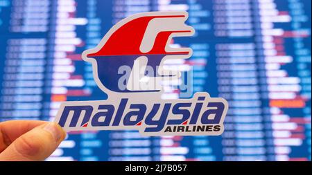 11. Dezember 2021, Subang, Malaysia. Das Emblem der Malaysia Airlines vor dem Hintergrund einer elektronischen Anzeigetafel mit Flugplänen auf der i Stockfoto