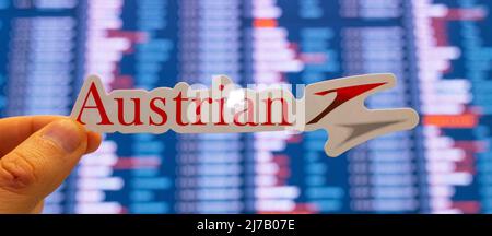 11. Dezember 2021, Wien, Österreich. Das Emblem der Austrian Airlines vor dem Hintergrund einer elektronischen Tafel mit Flugplänen auf der internationalen Flugbahn Stockfoto