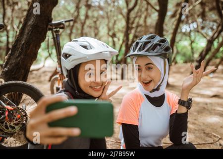 Zwei verschleierte Mädchen Selfie mit Handys während des Radfahrens Stockfoto