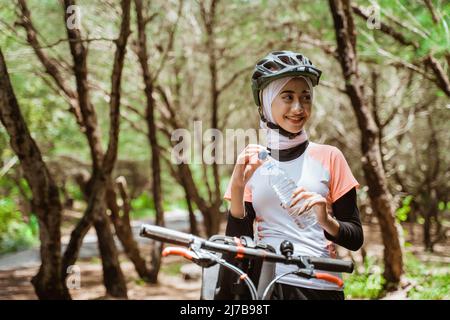 Sportliche Frau in Hijab öffnet Mineralwasserflasche Stockfoto
