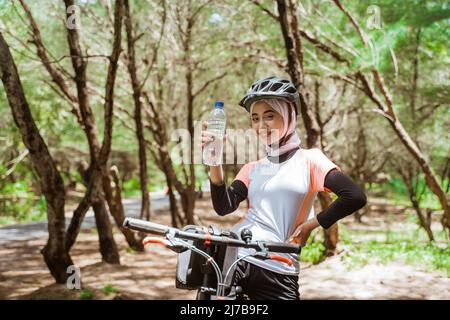 Schöne sportliche Frau in Hijab hält Flasche Stockfoto