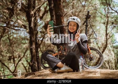 Verschleierte Mädchen lächelnd trägt Kopfhörer, während Selfie mit Handy Stockfoto