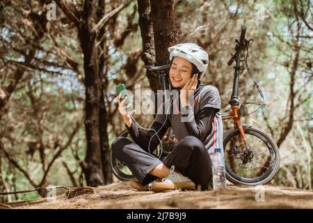 Verschleierte Mädchen tragen Kopfhörer Musik hören, während sitzend ruhen Stockfoto