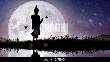 Silhouette von Buddha, der bei Nacht Vollmondlicht vermittelt. Tag von Magha Puja, Asanha Puja und Visakha Puja. Buddhistisches Feiertagskonzept. Stockfoto