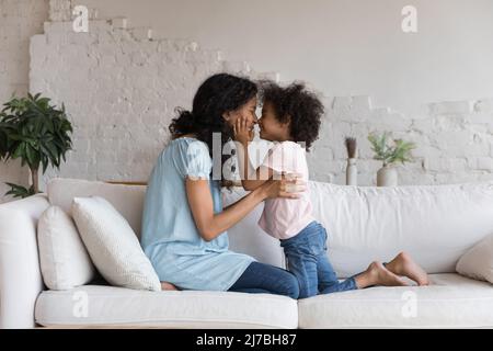 Glücklich liebend afrikanisch amerikanische Mutter küssen liebenswert Vorschule Tochter Stockfoto