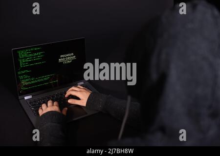 Konzept von Hacking und Malware. Hacker, der einen abstrakten Laptop mit einer digitalen Binärcode-Schnittstelle verwendet. Junger Hacker im Cybersecurity-Konzept. Stockfoto