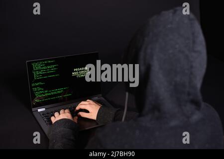 Konzept von Hacking und Malware. Hacker, der einen abstrakten Laptop mit einer digitalen Binärcode-Schnittstelle verwendet. Junger Hacker im Cybersecurity-Konzept. Stockfoto