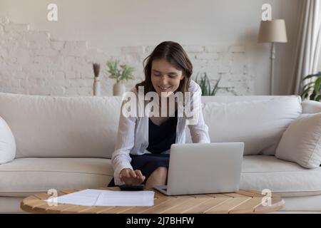 Positiv zufriedene junge Mieterin, die buchhalterische Arbeit macht Stockfoto
