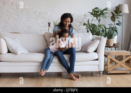 Freudige Mutter lehrt Tochter Kind Online-Learning-App zu verwenden Stockfoto