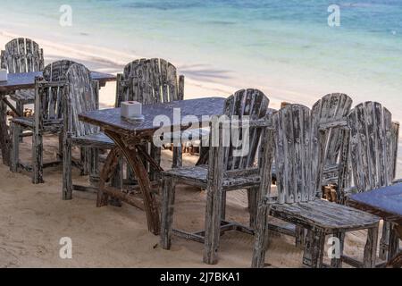 Holztisch und Stühle in leerem Strandcafé neben dem Meerwasser in Nahaufnahme. Insel Koh Phangan, Thailand Stockfoto