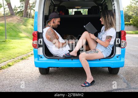 Das junge tätowierte Paar las und arbeitete im hinteren Teil des Wagens. Stockfoto