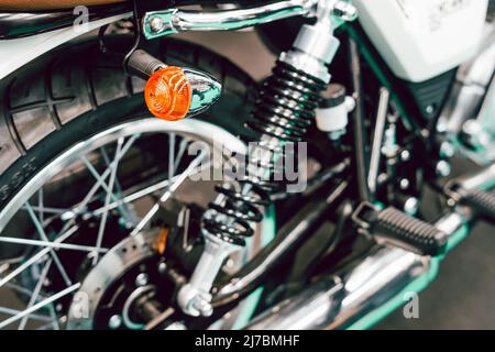 Detail der Fahrwerksfedern und Blinker am Hinterrad eines Custom Motorrads Stockfoto
