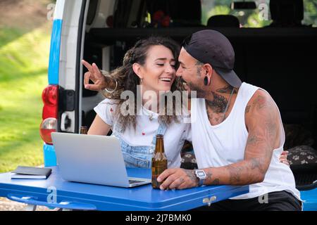 Ein junges tätowierte Paar, das sich während einer Reise im Van ansah und lächelte. Stockfoto