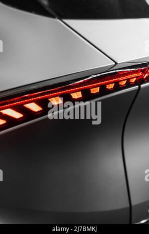 Ultramoderne matte Metallstruktur mit geschwungenen Formen und einem roten Kunststoff mit Licht von hinten und futuristischer Atmosphäre Stockfoto