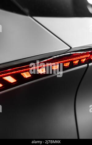 Ultramoderne matte Metallstruktur mit geschwungenen Formen und einem roten Kunststoff mit Licht von hinten und futuristischer Atmosphäre Stockfoto