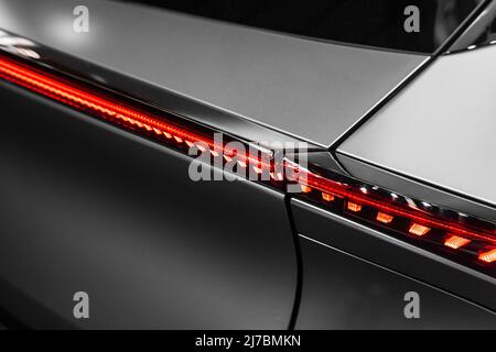 Ultramoderne matte Metallstruktur mit geschwungenen Formen und einem roten Kunststoff mit Licht von hinten und futuristischer Atmosphäre Stockfoto