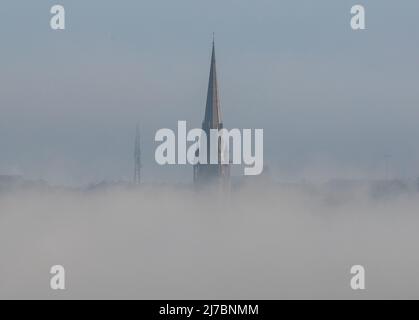 Cobh, Cork, Irland. 08.. Mai 2022. - Der Turm der St Colman's Cathedral ist über dem niedrigen Nebel in Cobh, Co. Cork, Irland, sichtbar. - Credit; David Creedon / Alamy Live News Stockfoto