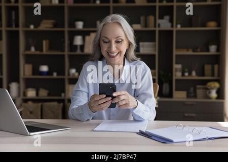 Glücklich reifen Smartphone-Nutzer Frau lesen Nachricht Stockfoto