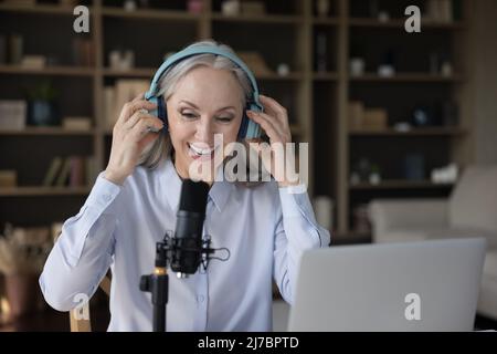 Reife Bloggerin Frau in Kopfhörer sprechen am professionellen Mikrofon Stockfoto